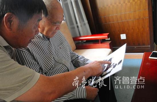 7月20日，在刘中华家中，刘国平和父亲翻看老照片。（齐鲁晚报·齐鲁壹点记者 赵波／摄）