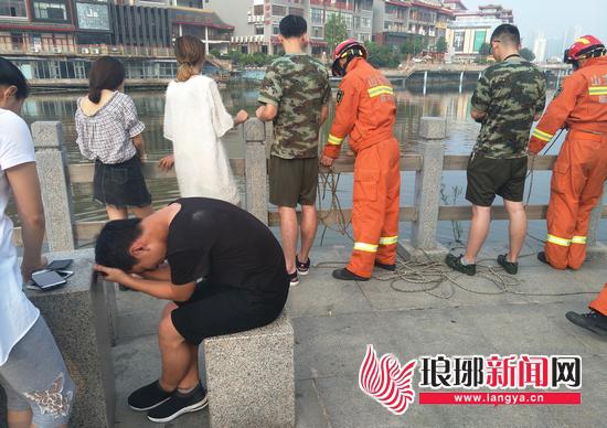小伙抱頭坐等,焦急盼著跳河的王某盡快被找到。