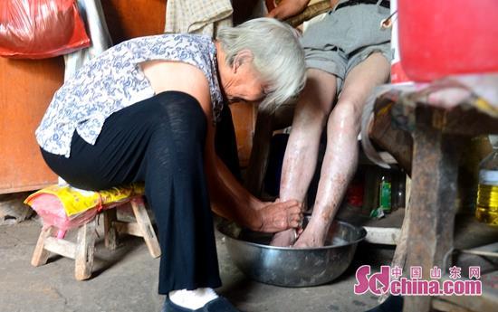 张玉英老人正在给儿子洗脚。