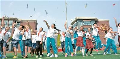 山东省蓬莱市第二实验小学东校区新建成后,学生们在操场上高兴地放飞纸飞机。(资料图片)
