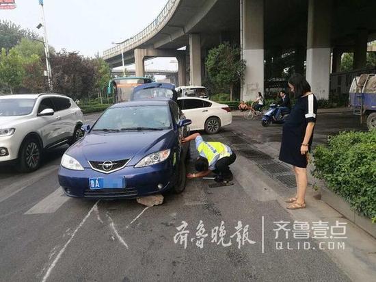 一怀孕在身的孕妇自己开车上班，途中不小心骑上了一块大石头，车辆顿时被卡在路中央进退不得，多亏交警帮忙，才得以脱困。