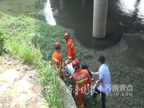 紧接着，消防官兵和120医护人员抬着担架，顺着河边小道接力将受伤男子抬至桥上，并送上120救护车。