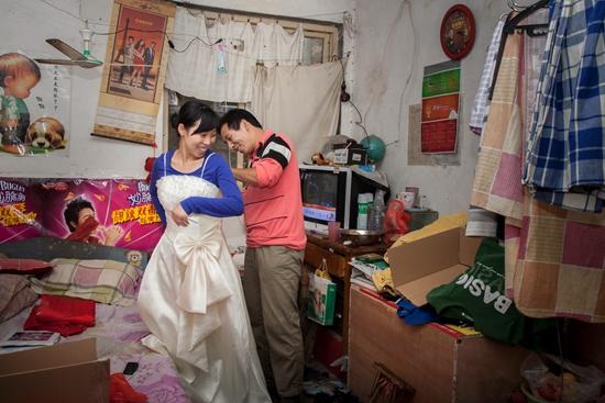 2011年9月16日，出租房内，王志宝帮妻子试穿租来的婚纱。