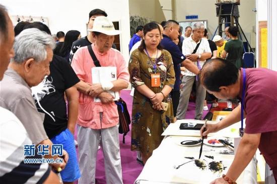 8月26日,觀眾在第五屆濟南藝術博覽會上觀賞一位書畫家現場作畫。新華社記者 馮杰 攝