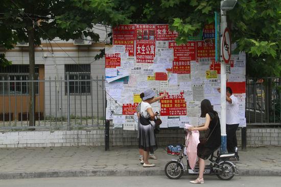 聊城文轩中学附近的公示栏上张贴有许多租房信息,许多家长正在从中寻找合适房源。 记者 李军 摄