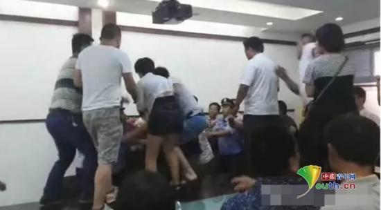 會(huì)議現(xiàn)場(chǎng)有人站在桌子上與院方調(diào)解人員發(fā)生沖突。
