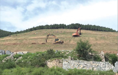 渣土山上，二十多位工人和三辆挖土机正在工作
