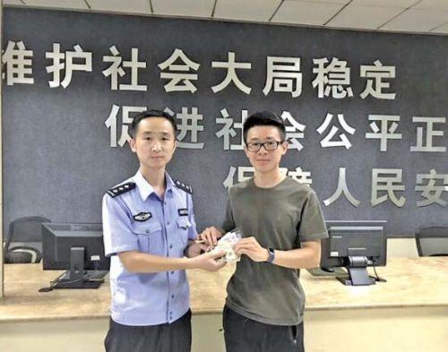 李驁從民警手中接過了自己丟失的錢包。 見習記者 劉曉 攝