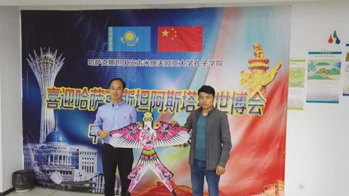 省政府新闻办主任魏长民(左)向哈萨克斯坦欧亚大学孔子学院赠送非遗产品潍坊风筝。