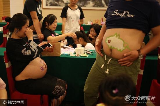 山東濰坊，十幾位準媽媽為迎接寶寶降生，在一彩繪現場由準爸爸們親手描繪肚皮彩繪，“孕”味十足。