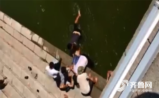 视频中，三名市民正在水中把一名女子往岸边拉，岸上几名市民接力抬起了落水者。