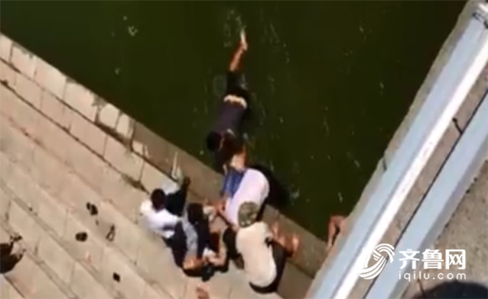 视频中,三名市民正在水中把一名女子往岸边拉,岸上几名市民接力抬起了落水者。
