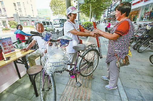 ②在洪楼南路附近，刘继芳给市民递打气筒。 记者刘玉乐 摄