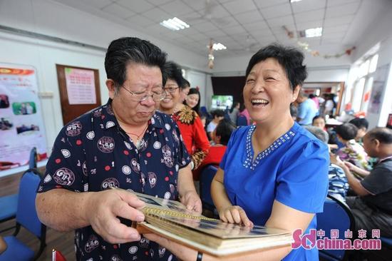 9月26日，青岛市30名老人与祖国同庆生日。图为邻里之间通过家庭相册回忆了家与国息息相关的发展历程。