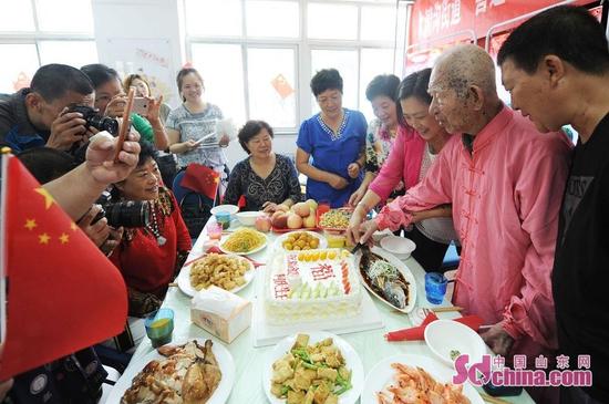 9月26日，青岛市30名老人与祖国同庆生日。图为前来参加生日庆祝活动的唯一的一位百岁老人切开蛋糕，表达对祖国生日的祝福。