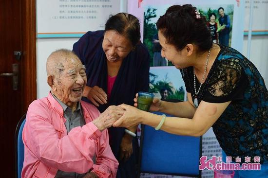 9月26日，青岛市30名老人与祖国同庆生日。图为社区居民向在座唯一的一位百岁老人敬茶祝福。