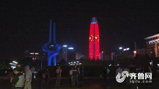 夜幕降临，华灯闪烁中，303米高的济南第一高楼绿地中心披上了五星红旗，并发出了国庆节的祝福语，喜迎祖国68岁的生日。