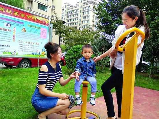 9月27日，居民张云和孩子在小区内健身广场玩耍。