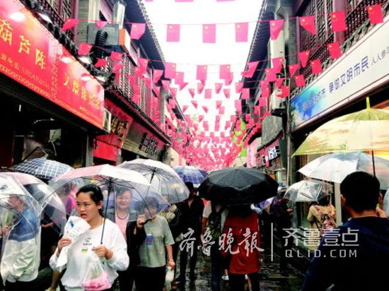 7日下午,下雨挡不住游客进入芙蓉街的脚步。