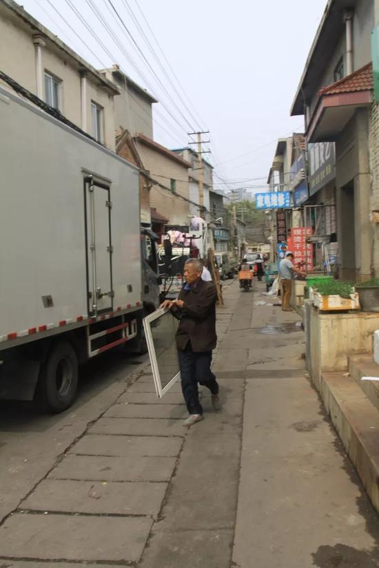 一位老者,将家里的窗纱搬上了车。