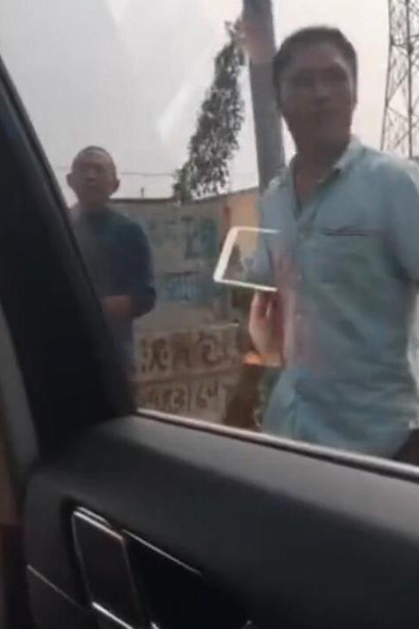 两人在阻挡车辆的绕行村内道路时发现了“商机”,向绕路车辆索要钱财作为“过路费”,不然不让车辆通行。(视频截图)