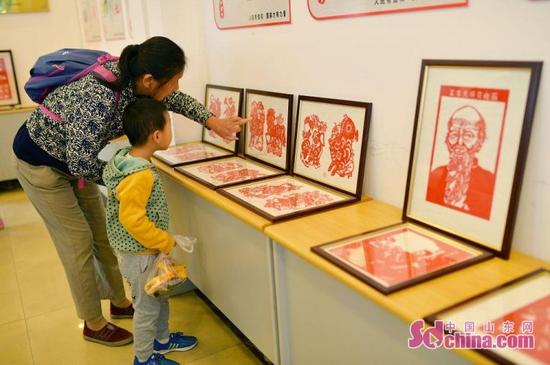 10月12日，在青島市滄口公園鄰里中心，社區居民參觀“喜迎十九大”剪紙作品展。