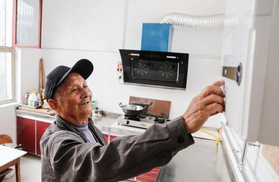 经过简单的讲解，73岁的老人张光廷也可以熟练操作燃气壁挂炉。记者 李岩松 摄