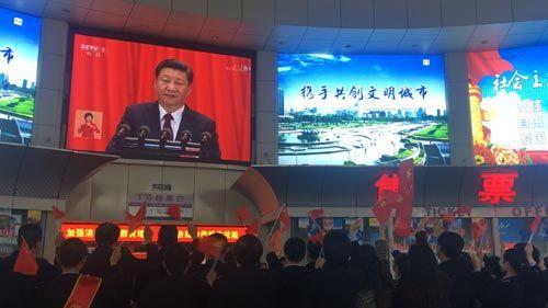 濟南長途汽車站通過車站大屏幕對十九大開幕會進行實時轉(zhuǎn)播，吸引了不少旅客駐足觀看。