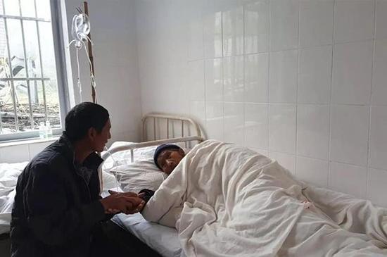 母亲躺在病床上输液，汪克武守候在旁紧握着母亲的手。刘苏瑶 图