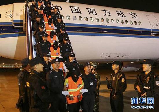 民警将犯罪嫌疑人押解下飞机。  新华网图