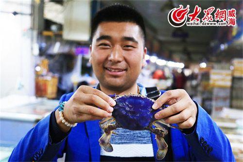 从青海来威海出差的白先生,见到蓝色螃蟹后非常惊讶,与蓝螃蟹合影