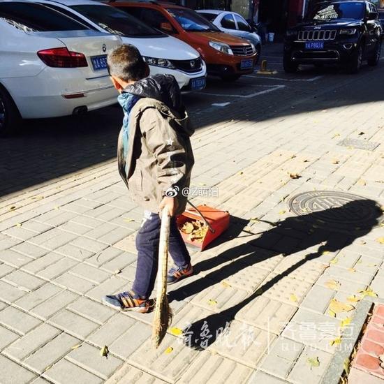 一个小男孩在帮环卫工妈妈扫大街、倒垃圾……
