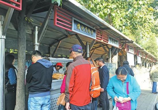 9:20左右，侯记煎饼果摊位前仍有多位顾客排队等待。(王希涛 摄)