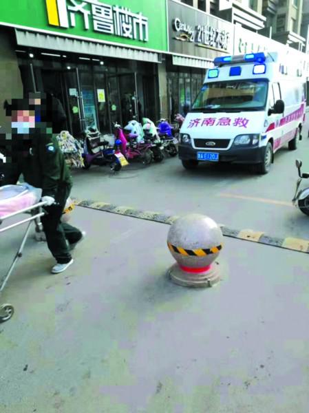 救护车被隔离墩挡住,救护人员只能用担架将孕妇抬到车上