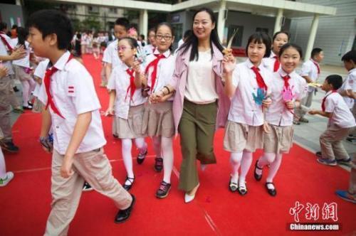 资料图:教师节,老师们牵着学生的手走过红地毯步入校园。张云 摄