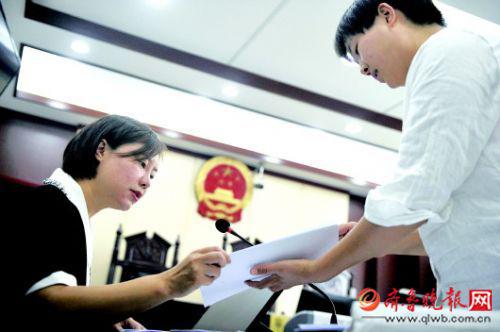 在济南市历下区人民法院，李卉正在和助理整理材料，为开庭做准备。