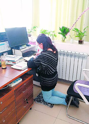 楊老師在辦公桌前“跪著”批改作業。
