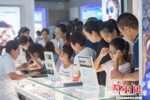 资料图:小学生们在柜台前挑选眼镜样式。韦亮 摄