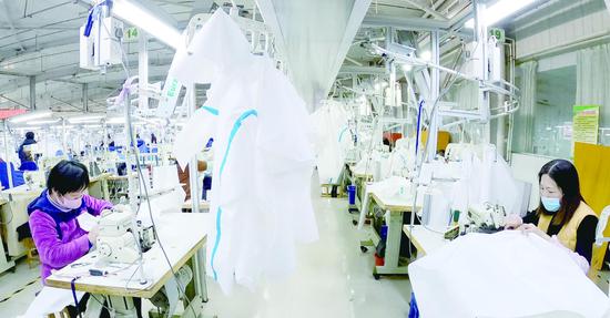◆山东盛原服装有限公司生产车间，工人们加班加点生产医用防护服。记者周坤摄