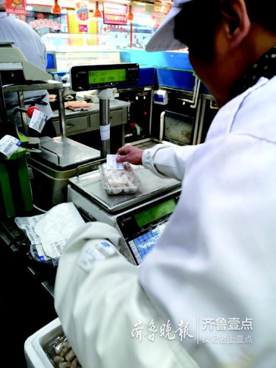 在歷下大潤發超市,工作人員正在為盒裝蝦仁去皮稱重。
