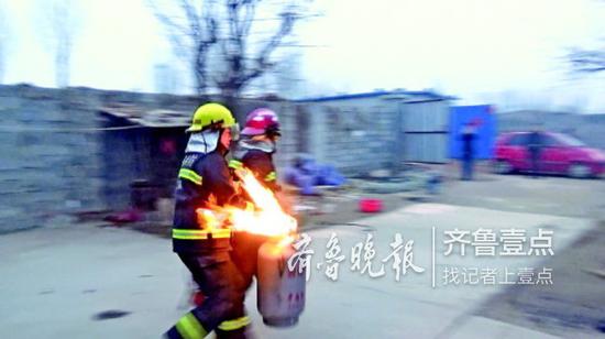 两位消防员搬着喷火的煤气罐飞奔到院里。 消防供图