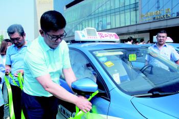 济宁华都房地产开发有限公司总经理周建强为出租车系上绿丝带。
