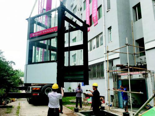济南市一老楼加装电梯现场,工作人员正在吊装电梯。本报记者　王杰　摄