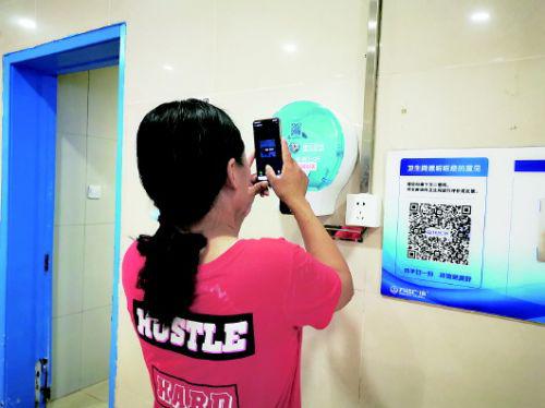 一位市民正在使用手机扫码取纸机器。