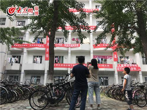 理工大夫妻校友回校园,在条幅前拍照