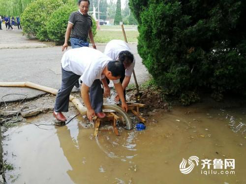 老师们正在弯腰清理积水，这份额外工作他们已忙了整整一个上午。