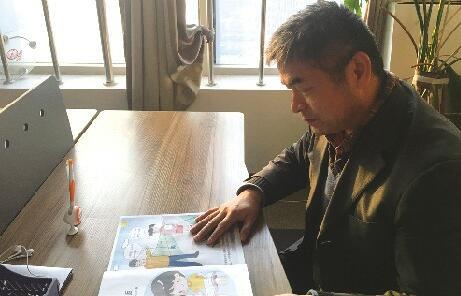 郭剛堂在檢查親子防拐繪本樣本。劉敏 攝