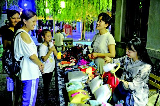 张慧母女正在百花洲夜市上向市民介绍手工制作的方法。