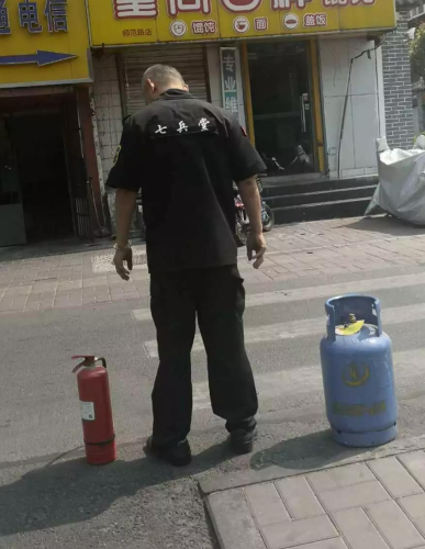 救火市民将煤气罐合力抱到着火住宅楼下。