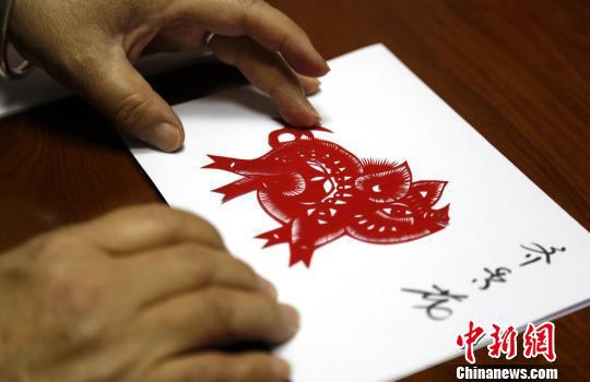 齊秀花正在將簡單的剪紙作品進行裝裱。 沙見龍 攝